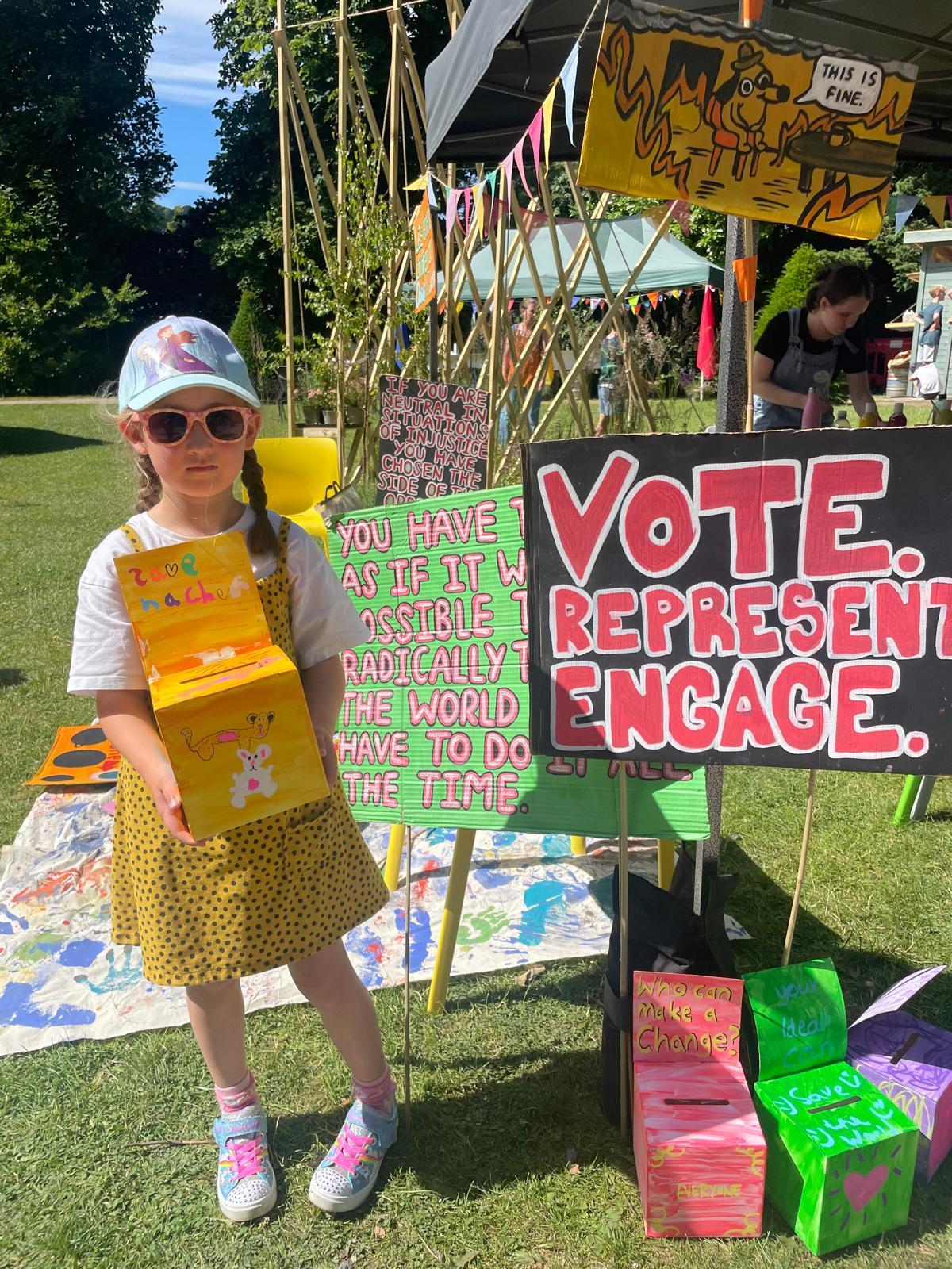 A child holding a box in front of signs

Description automatically generated